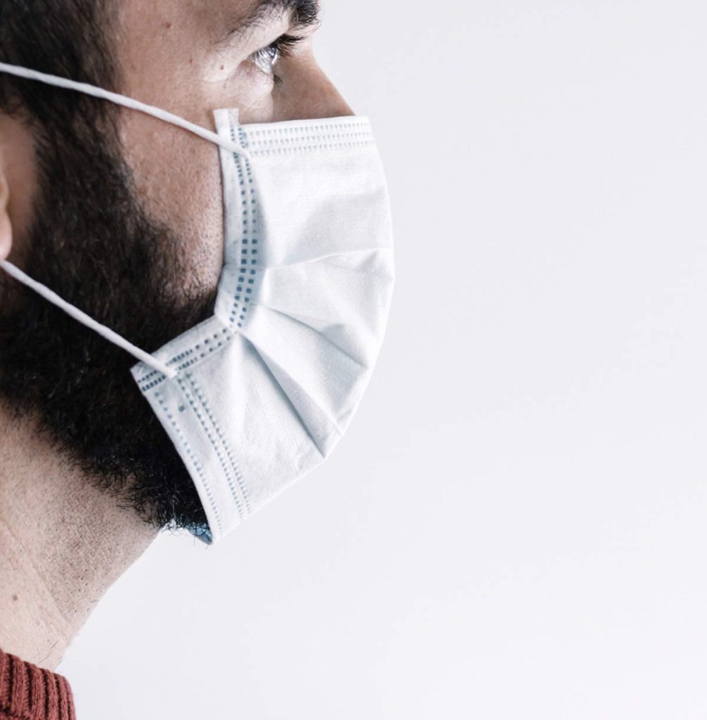 Close-up side view of a man wearing a medical face mask, highlighting COVID-19 healthcare safety measures.