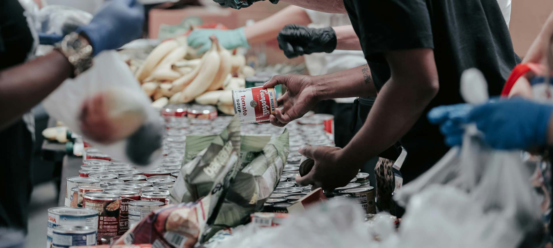 Volunteers organizing canned goods and fresh produce at a food donation or distribution center.