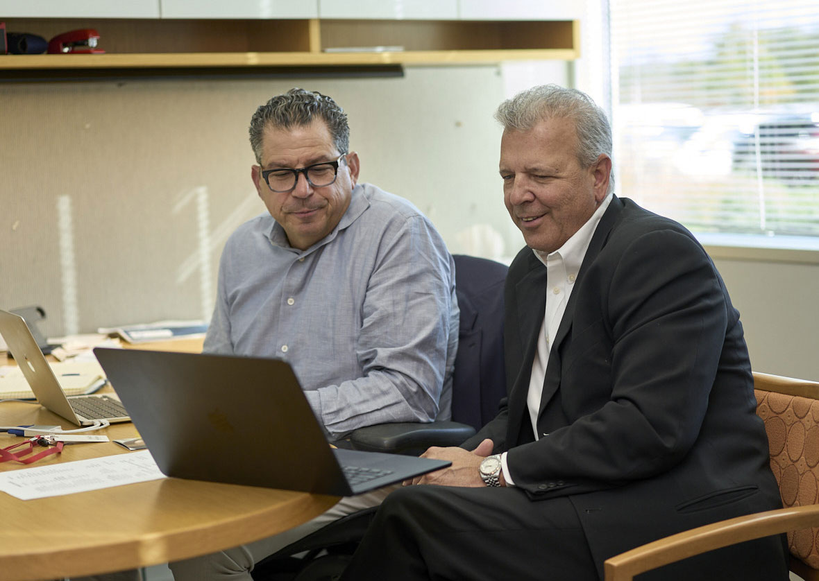 Two BlueStone members collaborate in an office while looking at a laptop screen.