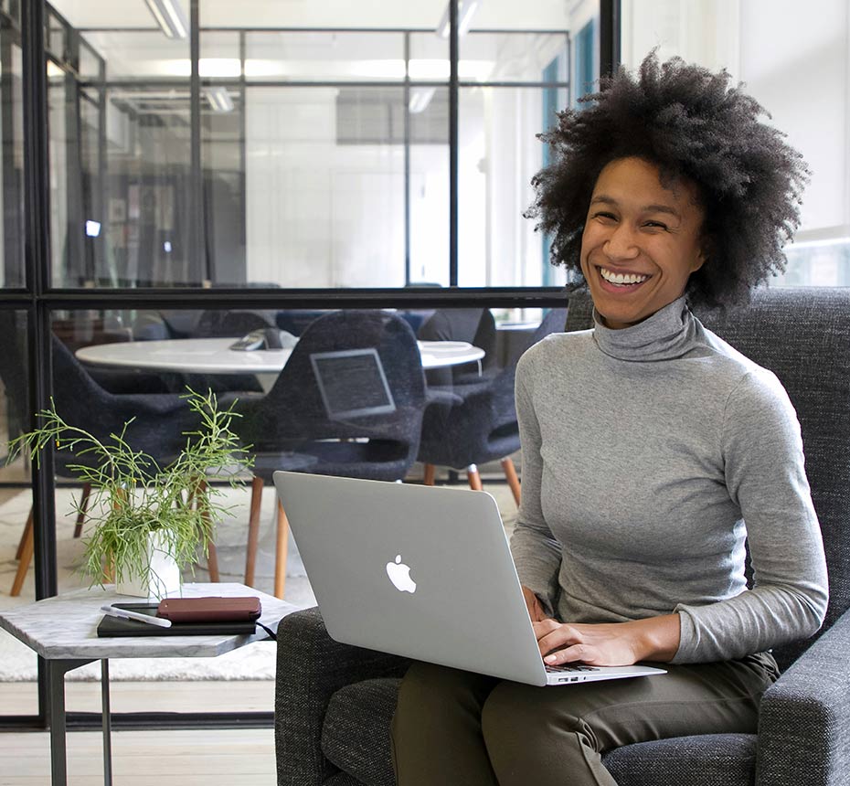 Women smiling while working at a computer in a modern office setting