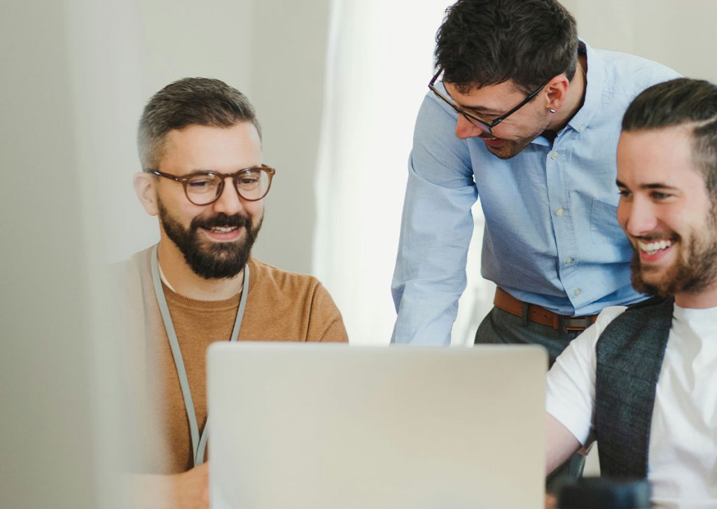 Small team collaborating over a laptop in an office setting, representing flexible and strategic workforce support