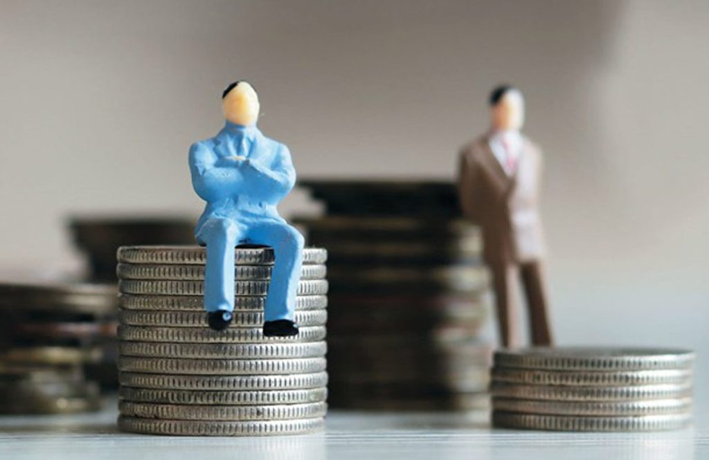 Two miniature figures sit on stacks of coins at different heights.